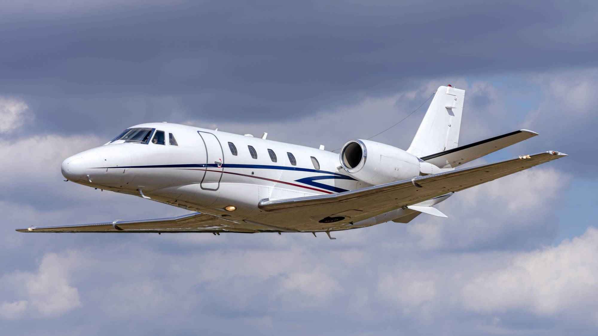 white-private-jet-flying-through-cloudy-blue-sky (1)