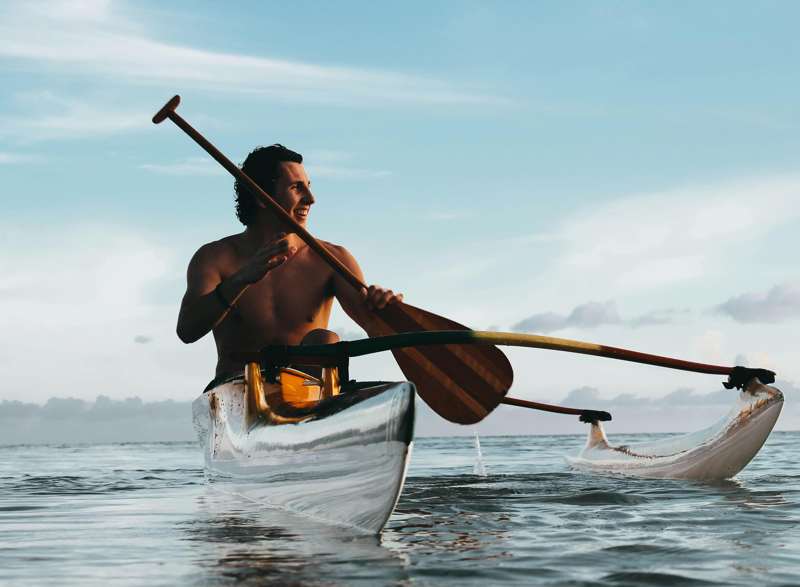 Turista pagaia nel mare di Tahiti su una canoa Polinesiana | FullPrivateJet