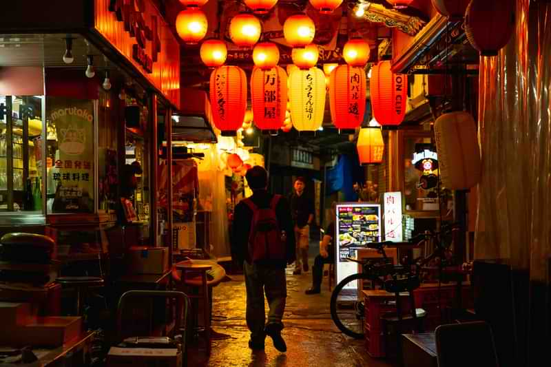 Turista passeggia di sera nel classico centro storico della città di Okinawa in Giappone | Fast Private Jet