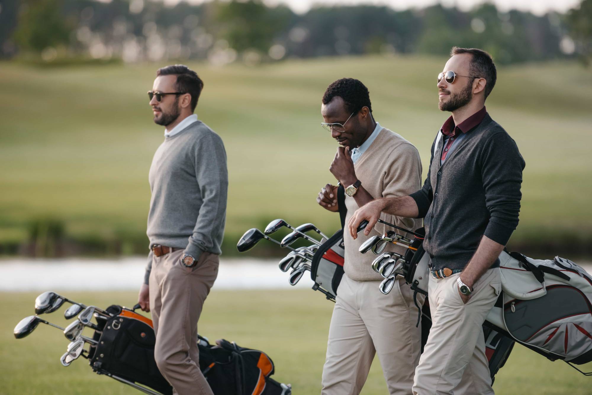 Three men walking on a golf course with golf bags